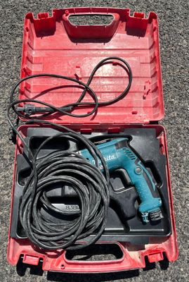 a corded drill in a red case on the ground