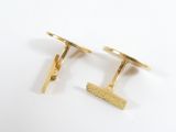 two pairs of gold cufflinks with a comb on a white surface