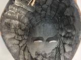 a wooden sculpture of a woman ' s face hanging on a wall