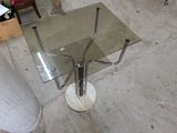 une table en verre avec une base en métal et un plateau en verre