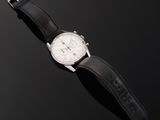 a close up of a watch on a black surface with a black background