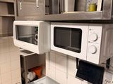 une casserole posée sur une cuisinière dans une cuisine, avec un micro-ondes au-dessus