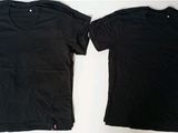 two black t - shirts sitting next to each other on a table