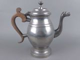 an antique silver teapot with a wooden handle on a grey background