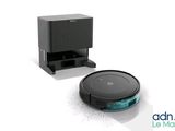 a close up of a robot vacuum and a box on a white surface
