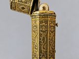 un briquet antique doré avec un boîtier métallique sur fond gris
