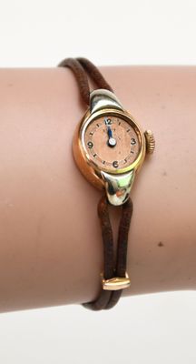 Quelqu'un porte une montre-bracelet avec un bracelet en cuir marron.