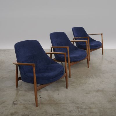 trois chaises bleues dans une pièce au sol en béton et aux murs blancs