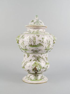 a white and green vase with a lid on a stand