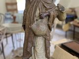 a statue of a woman holding a pot on a table