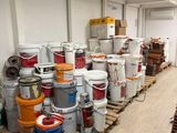 de nombreux seaux de peinture posés sur des palettes dans une pièce