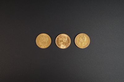 trois pièces d'or posées sur une surface noire