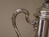 a silver tea pot sitting on a table next to a cup