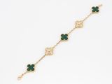 a close up of a gold bracelet with green clover charms