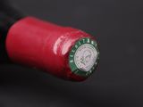 a close up of a red wine bottle with a clock on it