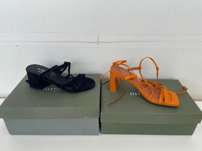 Deux paires de chaussures orange et noires sont posées sur une boîte.