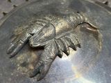 a close up of a metal object with a lobster on it