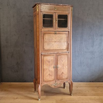 une vieille armoire en bois avec une porte vitrée, posée sur un parquet en bois massif