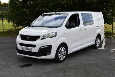 la camionnette blanche est garée sur le parking à côté des arbres