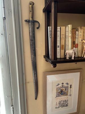 une photo d'un mur sur lequel sont posés des livres et une épée