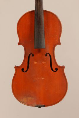 an old violin hanging from a string on a white wall