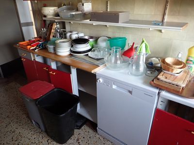 une petite cuisine avec beaucoup de vaisselle et de plats posés sur le plan de travail