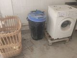 a washing machine and a trash can in a dirty room