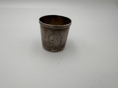 une vieille coupe en argent portant un monogramme sur un fond blanc