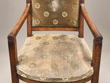 une vieille chaise en bois dont l'assise est recouverte d'un tissu à motifs floraux