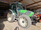 un homme debout à côté d'un tracteur dans une grange