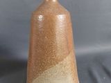 un vase brun posé sur une table à fond gris