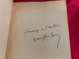 un livre ouvert, portant une signature manuscrite, posé sur un tissu rouge