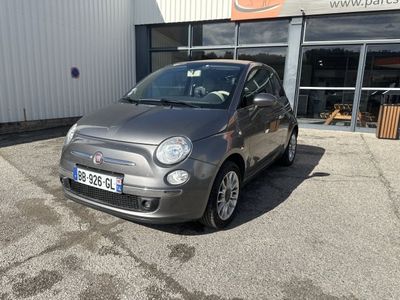 La petite voiture est garée devant un grand immeuble.