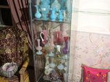 une vitrine dans un coin de la pièce, avec une chaise et un tapis