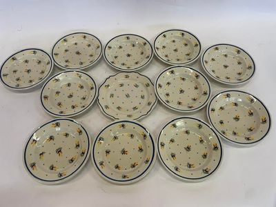 douze assiettes ornées d'abeilles, posées sur une surface blanche