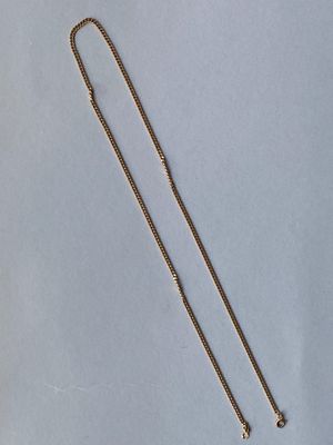 un collier en or muni d'une chaîne, sur fond bleu