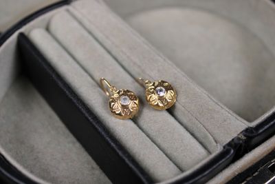 a pair of gold earrings sitting in a case