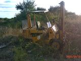 a tractor that is sitting in the grass by a pole
