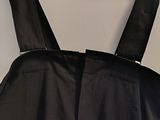 the back of a black dress hanging on a hanger on a wall