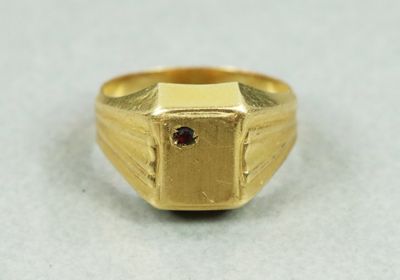 Gros plan sur une bague en or ornée d'une pierre rouge