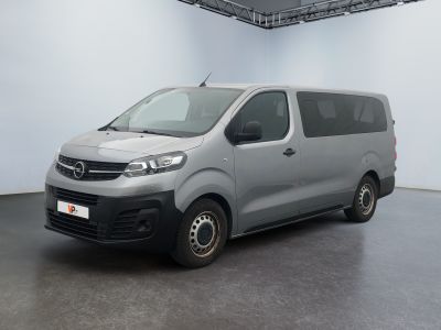 La camionnette argentée est garée dans une pièce blanche au sol noir.