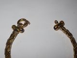 a close up of a gold bracelet on a white surface