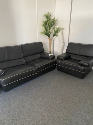deux canapés en cuir noir et un fauteuil dans une pièce où se trouve une plante