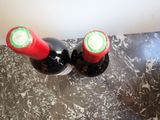 two bottles of wine sitting on a counter top