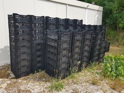 many black plastic crates stacked on top of each other in front of a building