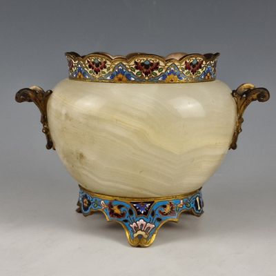 un vase blanc surmonté d'une couronne dorée