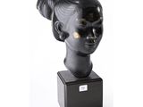 sculpture représentant la tête d'une femme coiffée d'un chignon, posée sur un socle noir
