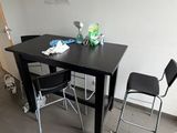 une table noire et deux chaises dans une petite pièce