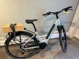 un vélo garé dans une pièce, avec un carton à l'arrière