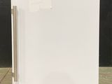 an image of a small white refrigerator on a concrete floor